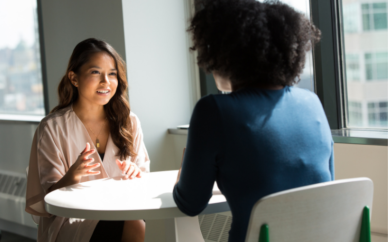 Chicas conversando sentadas a una mesa.