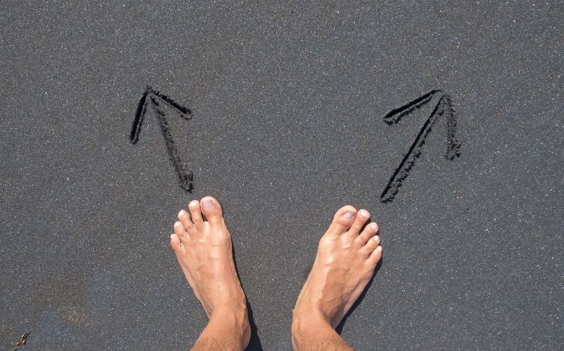 Pies en la playa con flechas marcado dos direcciones